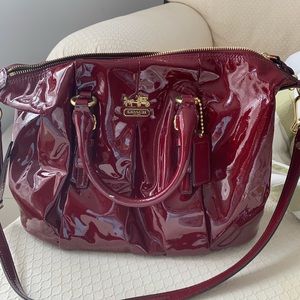 Coach dark patent leather red satchel with strap.